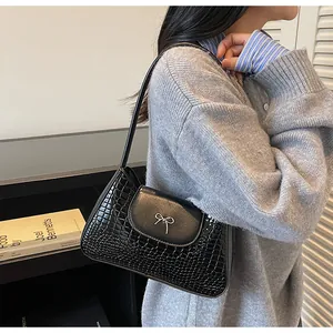 Détail du sac d'épaule noir avec gaufrage crocodile et boucle noeud en métal argenté