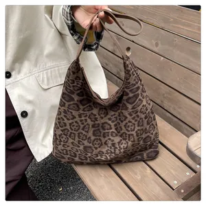 Macro view of leopard print texture and sturdy brown shoulder strap on a large hobo bag