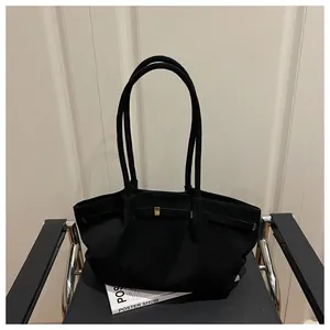 Detail of minimalist black tote bag with gold buckle on a stylish chair