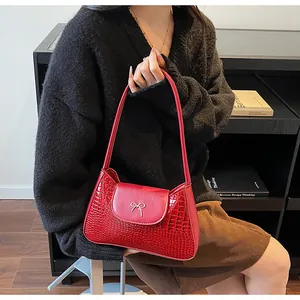 Détail du sac rouge à motif crocodile avec nœud métallique argenté élégant