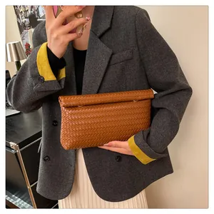 Close-up of brown woven leather clutch bag styled with a professional blazer