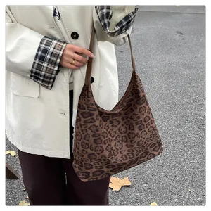 Close-up of leopard print hobo bag with a brown leather shoulder strap on a model