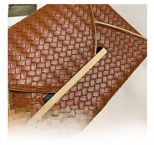 Primer plano de la textura trenzada marrón y el cierre dorado del elegante bolso de sobre