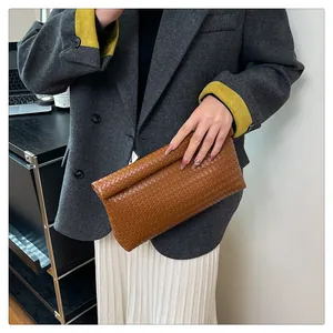 Chic caramel woven leather clutch bag styled with a professional grey business suit