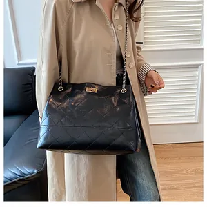 Détail du sac bandoulière matelassé noir avec chaîne dorée et fermoir pivotant