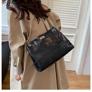 Détail du sac cabas matelassé noir avec fermoir doré et bandoulière en chaîne cuir
