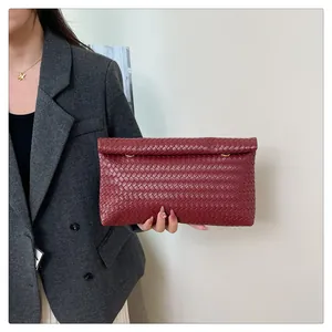 Detail of burgundy woven leather clutch bag with premium intrecciato texture and gold ring