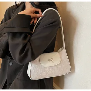 Détails de texture crocodile blanc et nœud métallique sur le sac à bandoulière