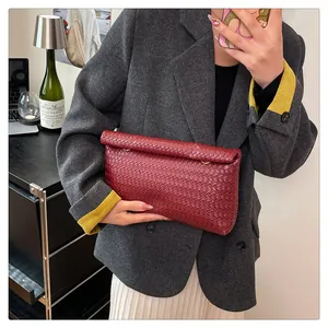 Close-up of a burgundy woven leather clutch bag with golden metal ring and flap