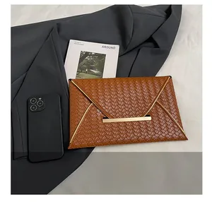 Primer plano de un bolso sobre marrón trenzado con hebilla dorada y smartphone de referencia