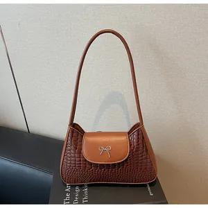 Détail du sac bandoulière marron motif crocodile avec un nœud en métal argenté