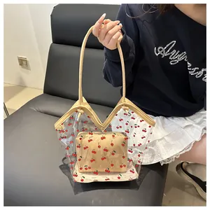 Detail of transparent PVC cherry print tote bag with beige leather handles and inner pouch