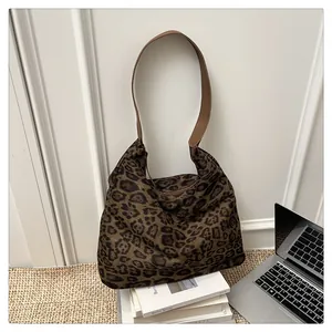 Close-up of leopard print canvas tote bag with brown leather strap on books