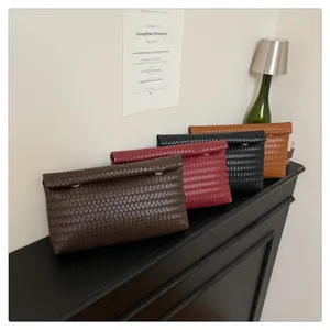Close-up of woven leather envelope clutch bags in dark brown, burgundy, black and tan shades
