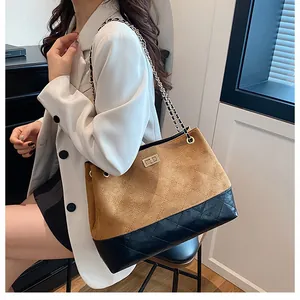 Détail du sac cabas en daim beige et cuir matelassé noir avec chaîne dorée sur mannequin