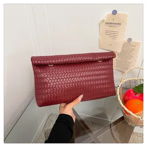 Detail showing the burgundy woven leather texture and gold buckle of the clutch bag