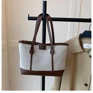 Detail of canvas tote bag with brown leather trim hanging on a minimalist display stand