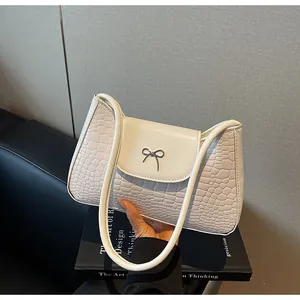 Détail du sac baguette crème avec texture crocodile et boucle nœud argenté