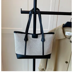 Detailed view of large tote bag in canvas and black leather hanging on a rack