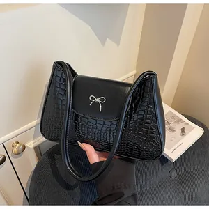 Détail de la texture crocodile noir et du nœud argenté sur le sac à bandoulière français