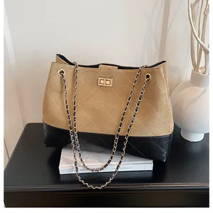 Détail d'un sac bandoulière matelassé avec daim bicolore, cuir et fermoir doré rotatif