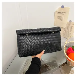 Close-up of black woven leather texture and magnetic flap on this large business clutch