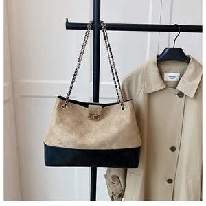 Détail d'un sac vintage en daim kaki, cuir noir matelassé et bandoulière en chaîne