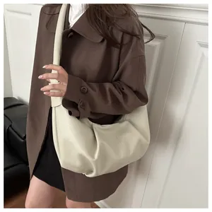 Macro detail of creamy white pleated leather texture and wide strap on minimalist crescent bag