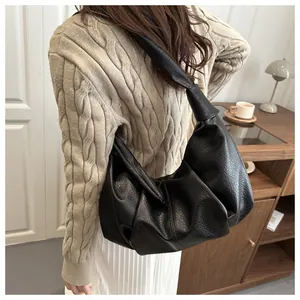 Detail view of black lychee texture hobo bag with knotted strap on shoulder
