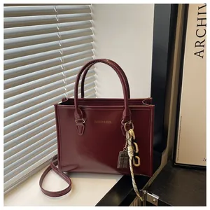 Détail du sac cabas bordeaux avec texte Fashion & Bags et breloque en chocolat