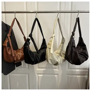 Row of pleated hobo bags in caramel, black, cream, and brown on a metal rack