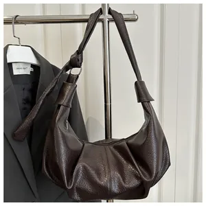 Detail of dark brown leather hobo bag with pebbled texture and knotted shoulder strap