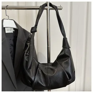 Detail of black lychee grain leather dumpling bag featuring soft cloud folds and knotted strap