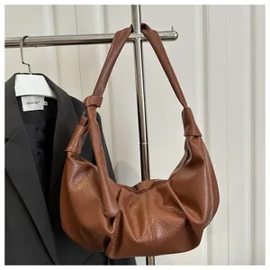 Close-up of brown pleated crescent shoulder bag with pebbled faux leather texture