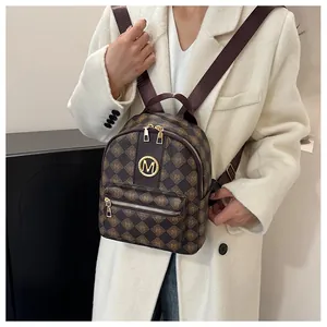 Detail of premium brown leather mini backpack with letter M pattern and metal logo