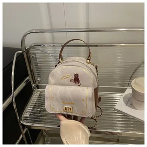 Gros plan sur le sac en tissu beige avec broderie chat et bandoulière en chaîne dorée