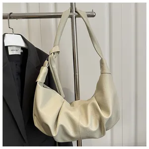 Close-up of beige pleated dumpling bag with knotted strap and lychee texture detail