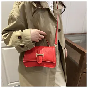 Detail showing red quilted handbag with golden H-shaped clasp and delicate faux leather texture