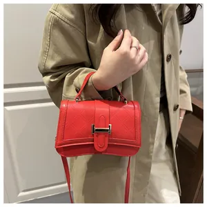 Detail of red quilted crossbody bag with gold buckle on khaki trench coat