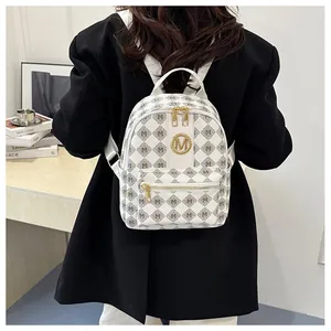 Detailed shot of stylish white backpack with golden M logo and letter pattern on model