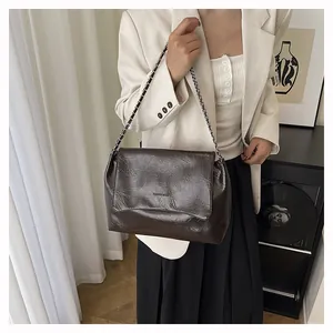 Detail of dark brown leather tote bag with chain strap and fashion bags embossed text