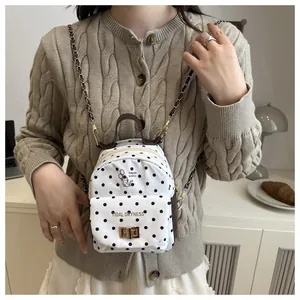Detailed close-up of mini polka dot backpack with cat print and gold chain strap