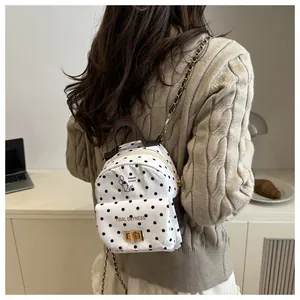 Polka dot mini backpack featuring golden turn-lock and chain strap on a model