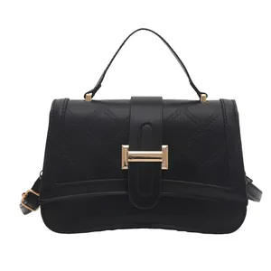 Quilted black crossbody bag with crescent base and gold buckle on white background