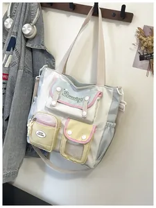 Detail of color-block nylon tote bag showing multiple functional pockets and embroidery