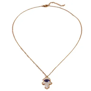 Gold Hamsa Hand necklace with blue Evil Eye crystal pendant on white background