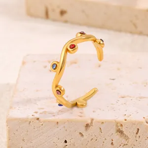 Minimalist 18K gold-plated titanium steel ring with colorful zircons on stone background