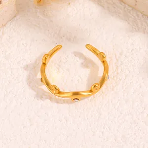 Detail of gold-plated wavy ring featuring five small white crystals and open design