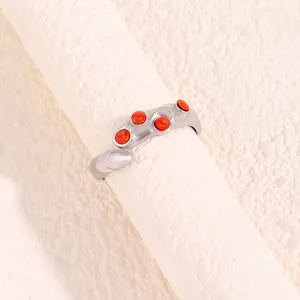 Gros plan sur une bague argentée irrégulière avec cinq cristaux rouge orangé
