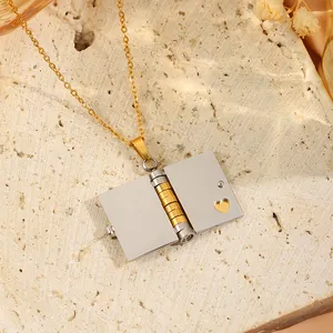 Détail du pendentif en forme de livre enveloppe ouvrant en acier bicolore or et argent